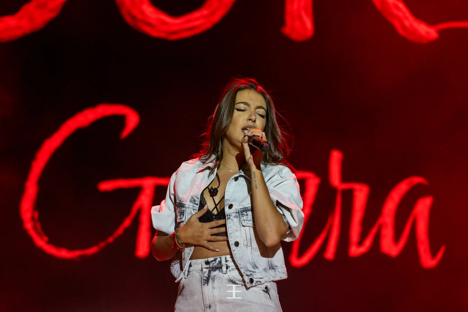 Ana Guerra canta con la mano en el pecho, recortada sobre las letras de neón rojo de su apellido