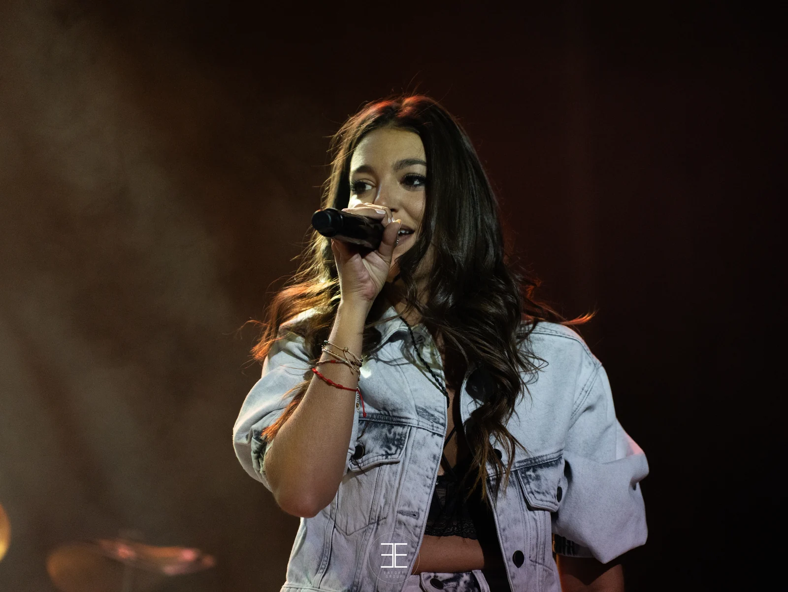 Primer plano de Ana Guerra cantando sobre un fondo marrón oscuro, con el pelo sobre la cara