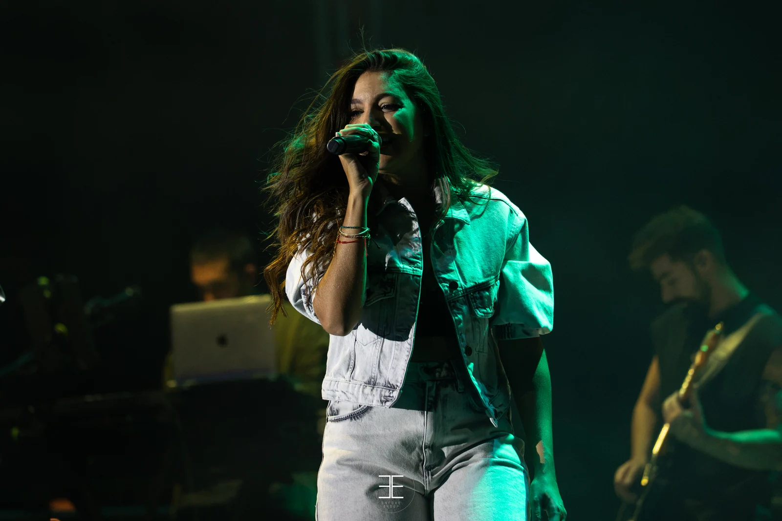 Ana Guerra canta bajo una luz verde, con un guitarrista desenfocado detrás