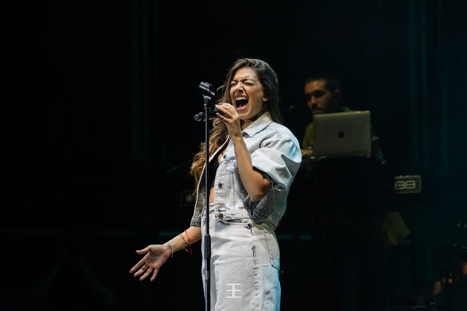 Ana Guerra canta con fuerza ante el micrófono de pie, con el teclista detrás