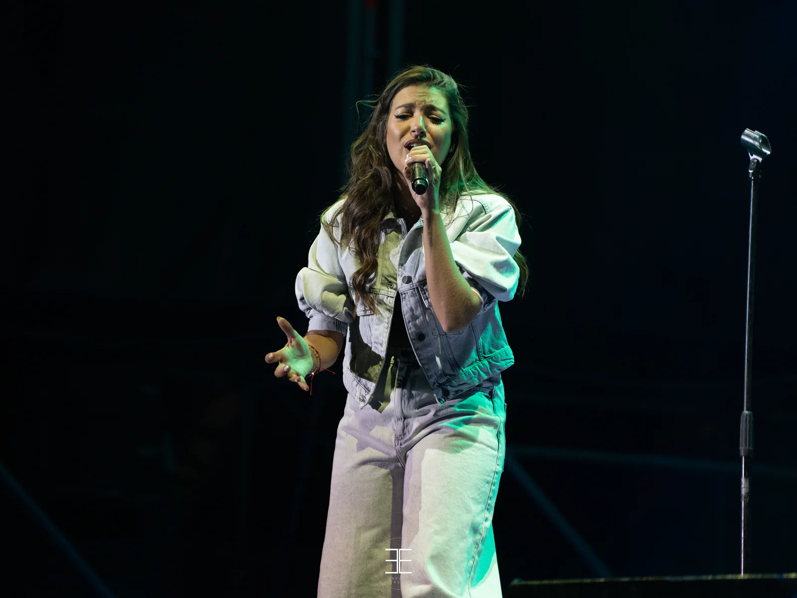 Ana Guerra canta bajo una luz verde con el brazo recogido