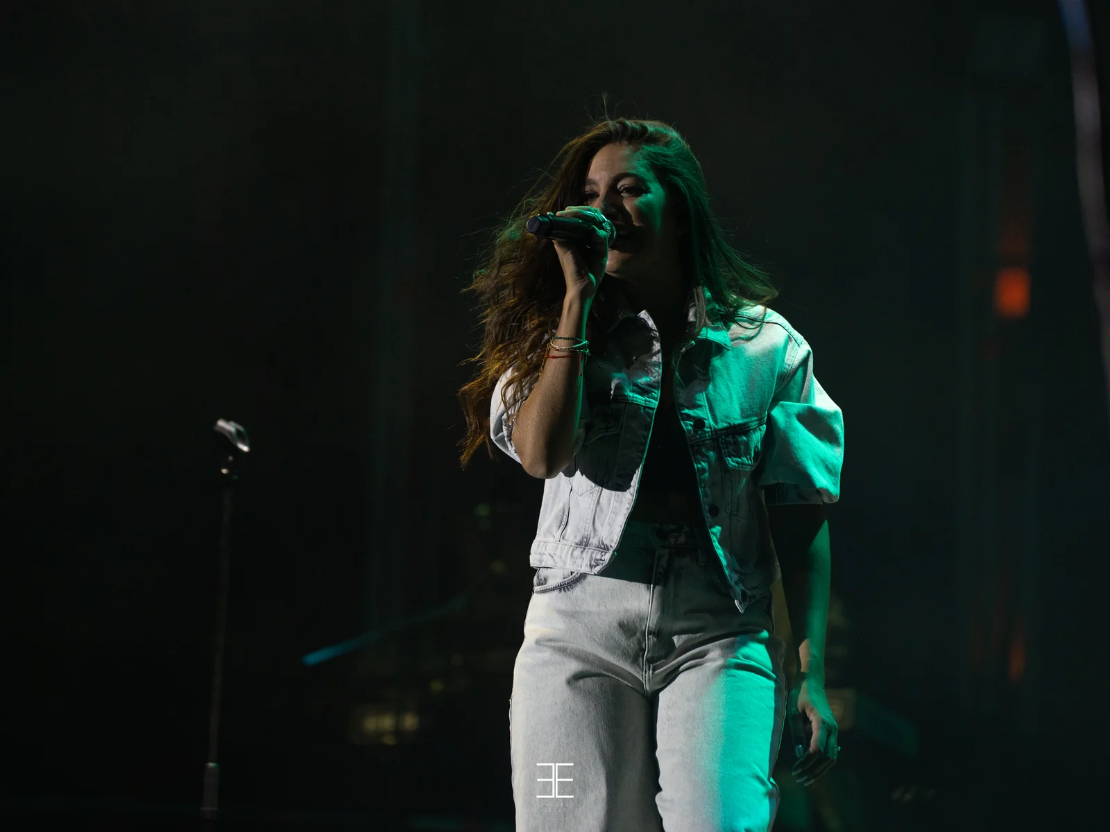 Primer plano de Ana Guerra cantando con los ojos cerrados bajo una luz verde