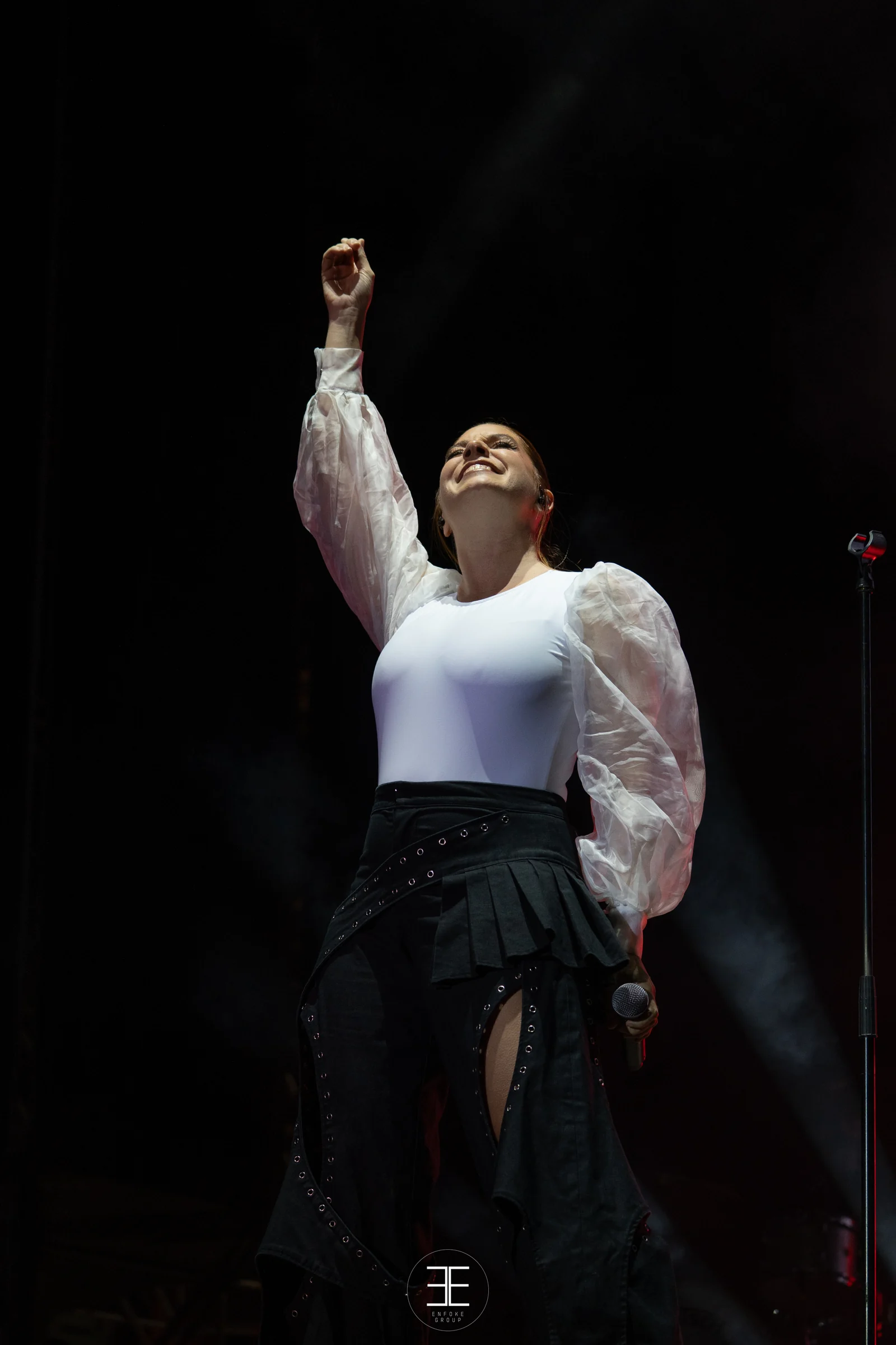 Leire Martínez, de cuerpo entero, levanta el puño cantando con body blanco y falda negra