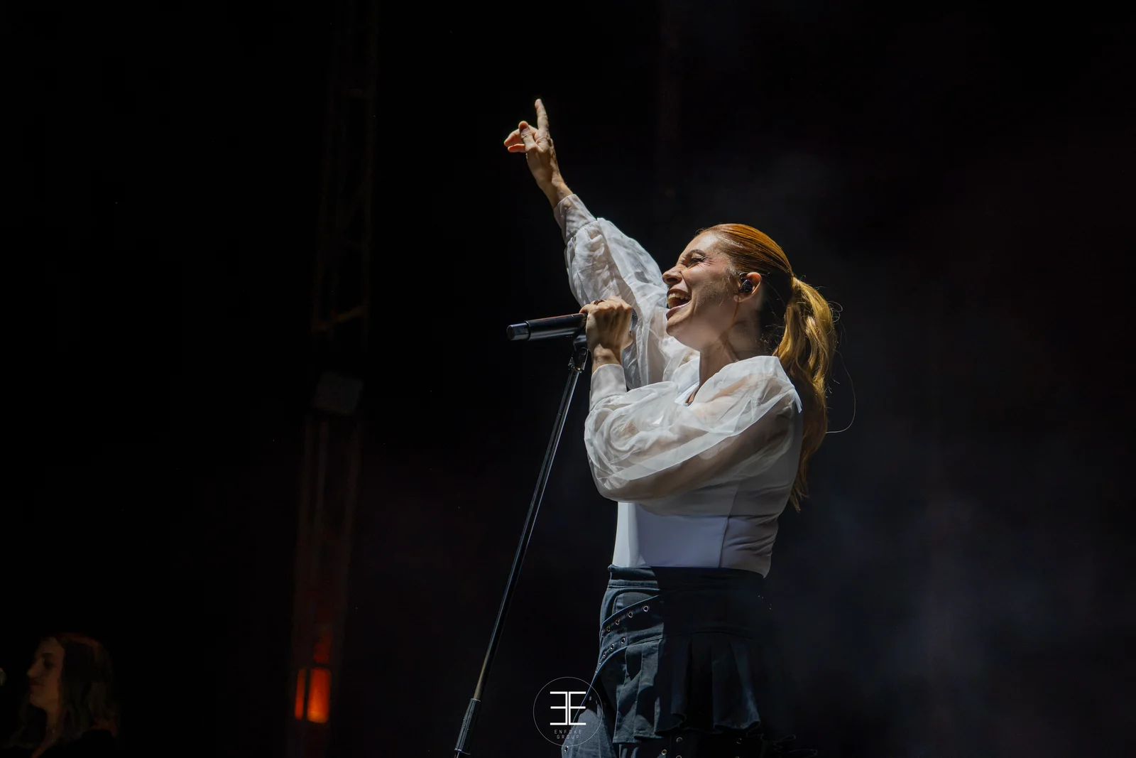Leire Martínez señala hacia arriba con un dedo mientras canta, entre humo