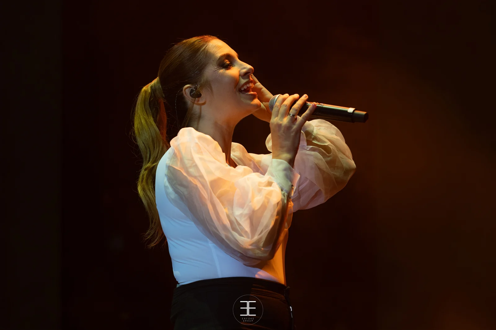 Primer plano de Leire Martínez cantando con el micrófono de mano bajo una luz cálida