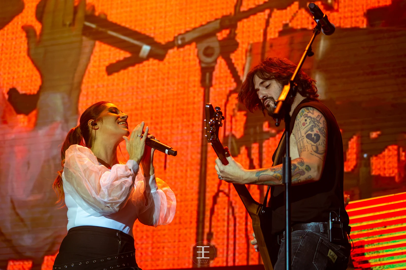 Leire Martínez canta junto al guitarrista, con la pantalla del escenario encendida en rojo detrás