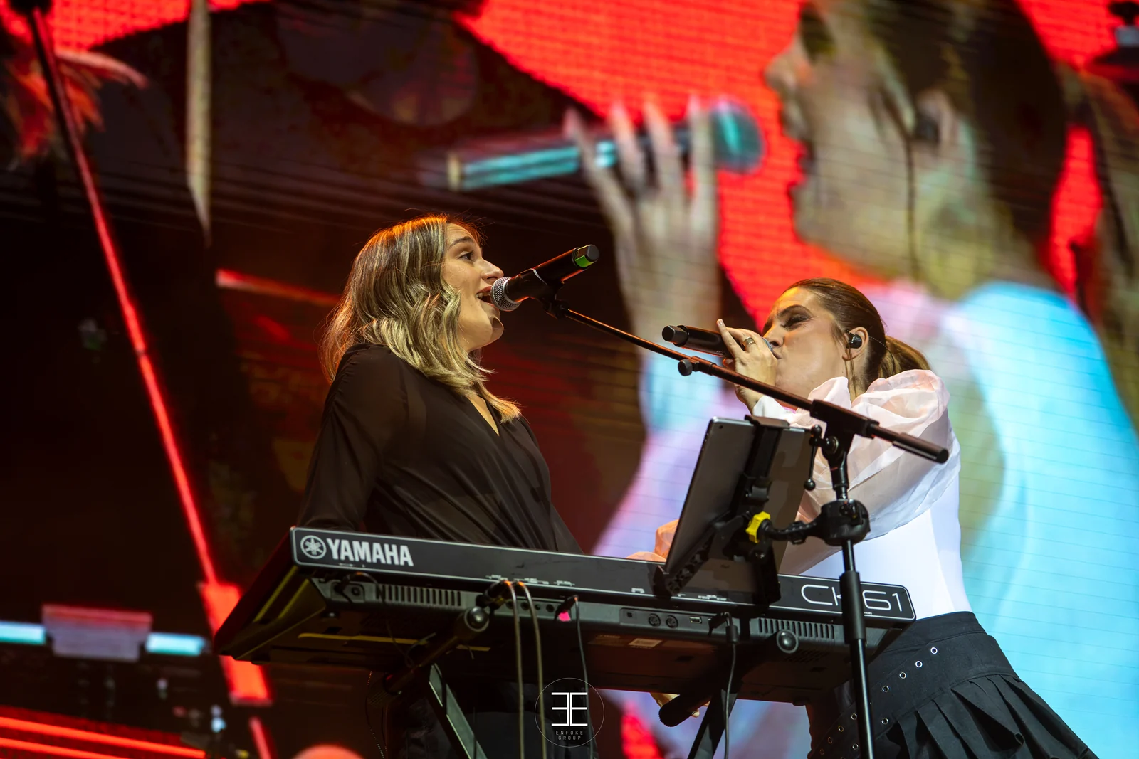 Leire Martínez y la teclista cantan cada una a su micrófono, muy cerca la una de la otra