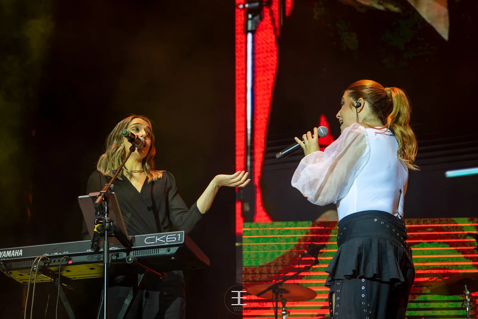 Plano abierto del escenario con la teclista a la izquierda y Leire Martínez a la derecha ante la pantalla