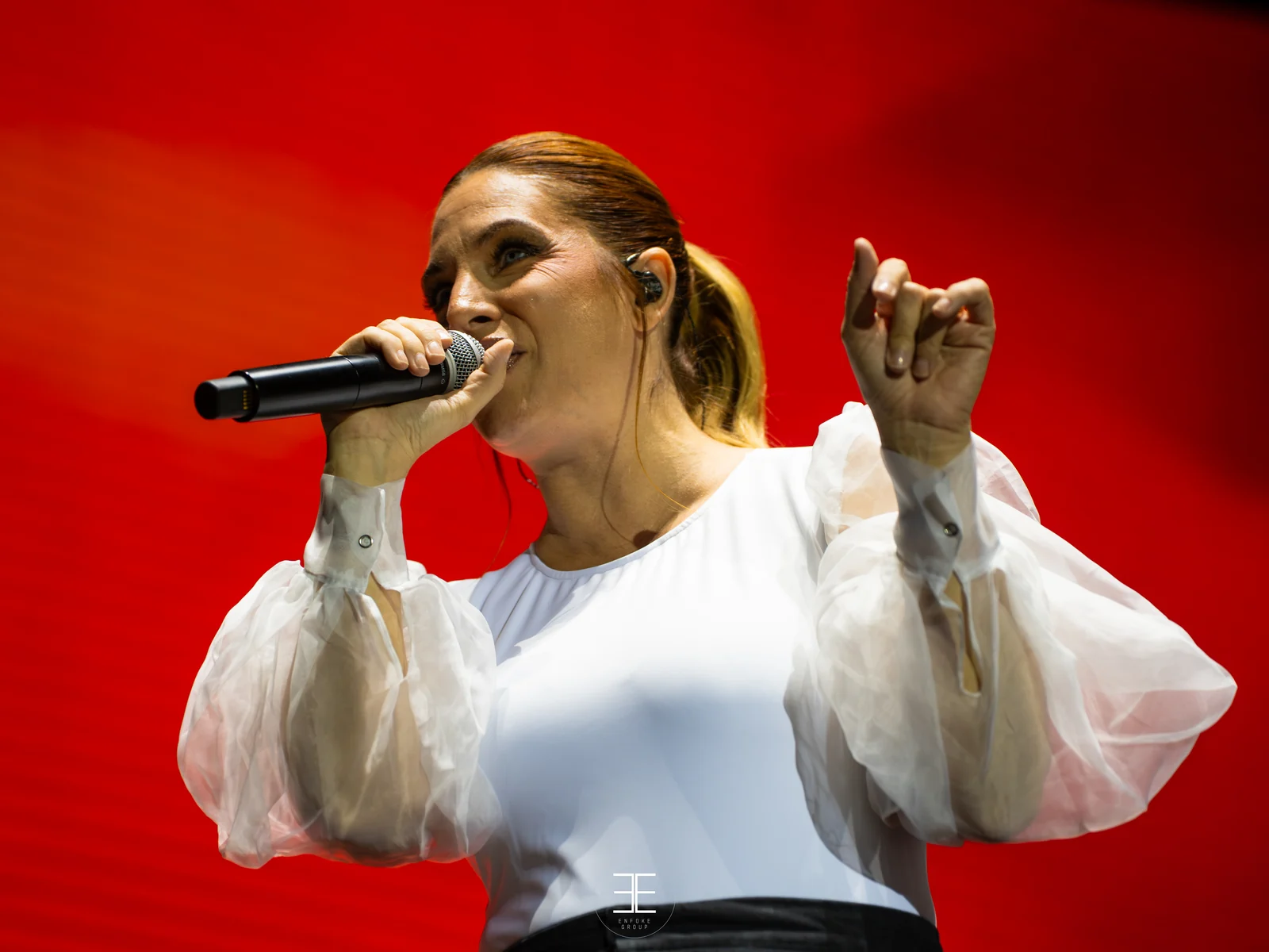 Leire Martínez canta con el micrófono de mano sobre un fondo rojo pleno