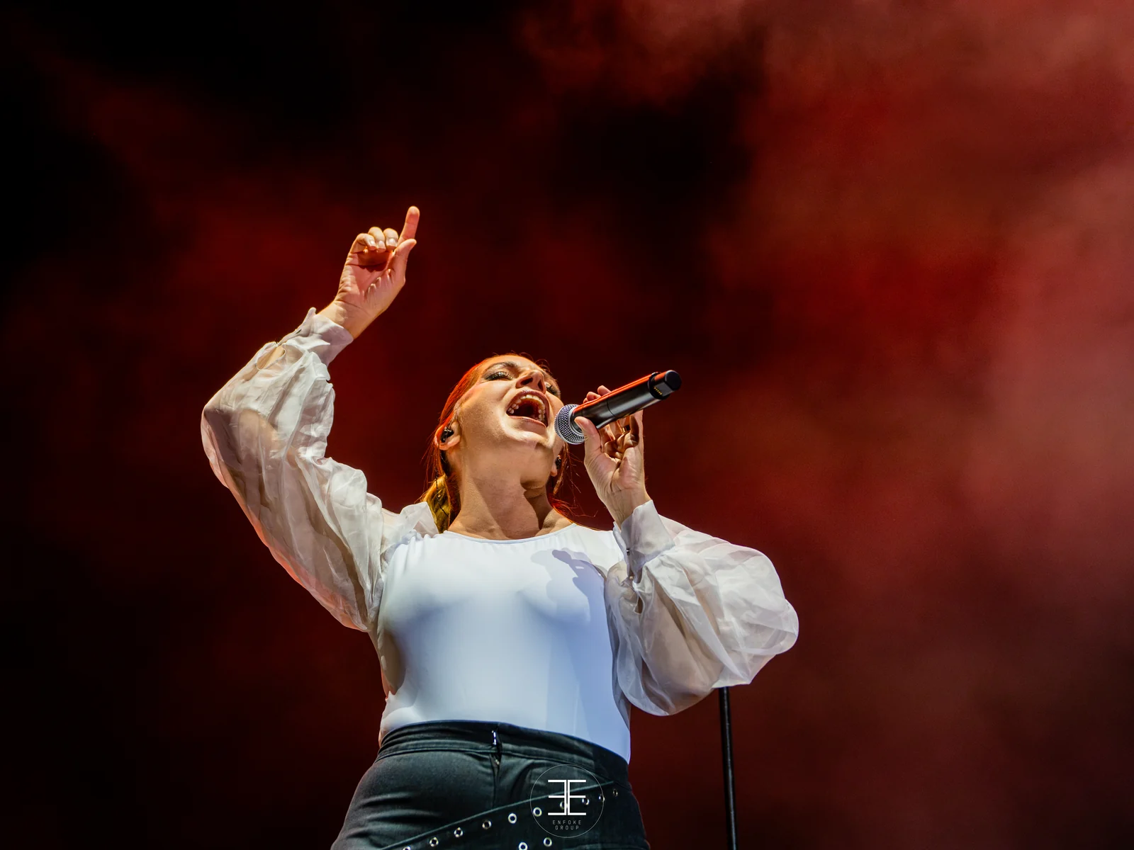Leire Martínez levanta un brazo señalando mientras canta, entre humo rojo