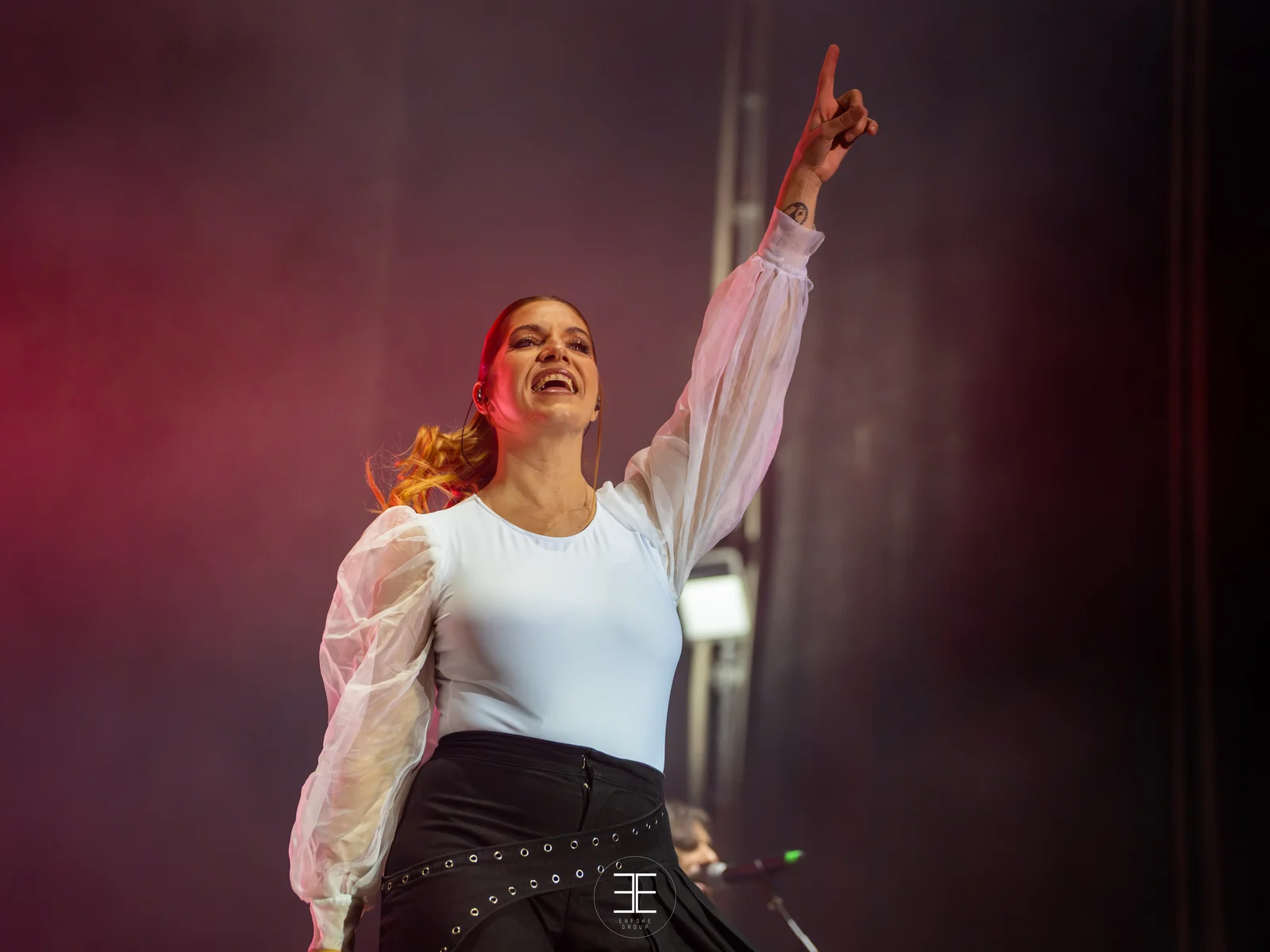 Leire Martínez canta con el brazo levantado y la mano abierta, entre humo
