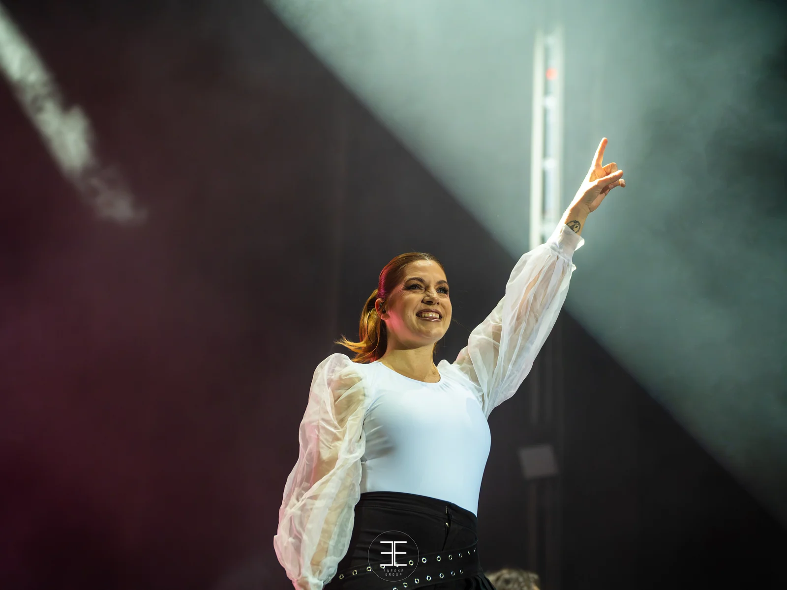 Leire Martínez levanta el brazo cantando, atravesada por un haz de luz lateral