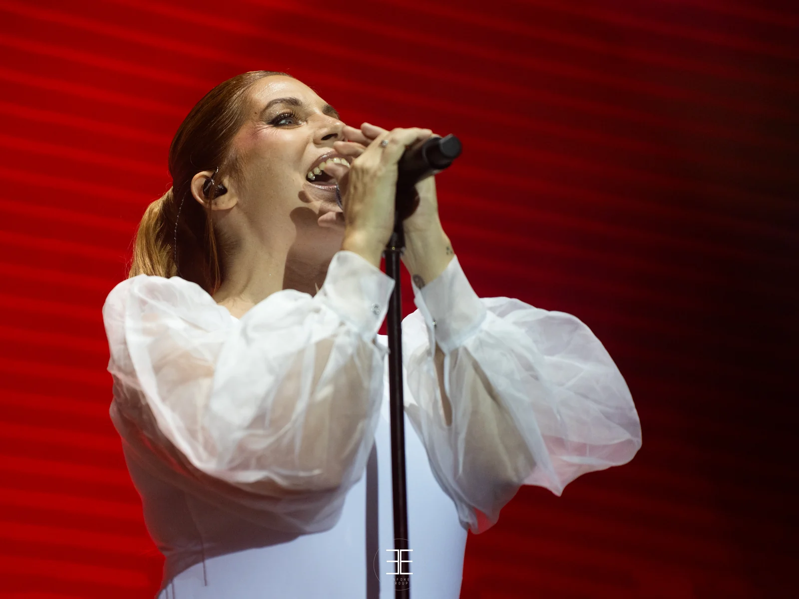 Primer plano de Leire Martínez cantando sobre un fondo rojo saturado
