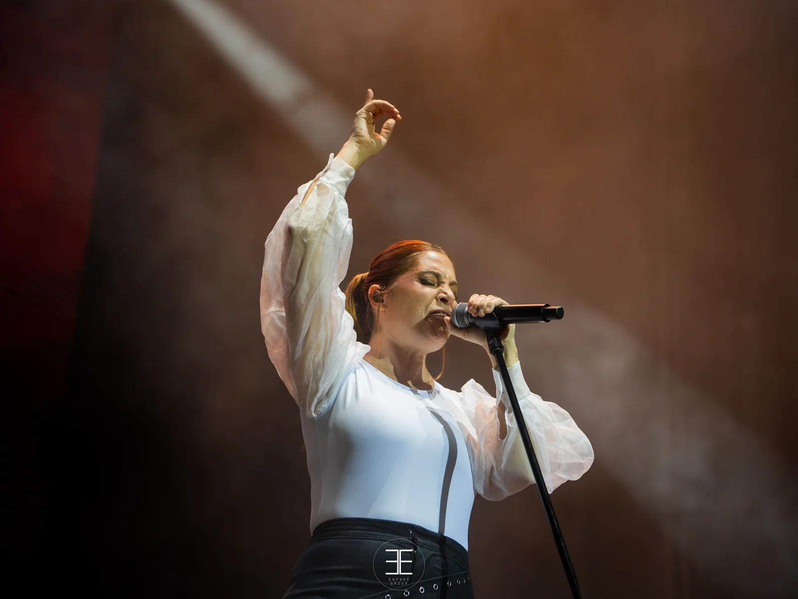 Leire Martínez canta con el brazo levantado bajo una luz cálida y marrón