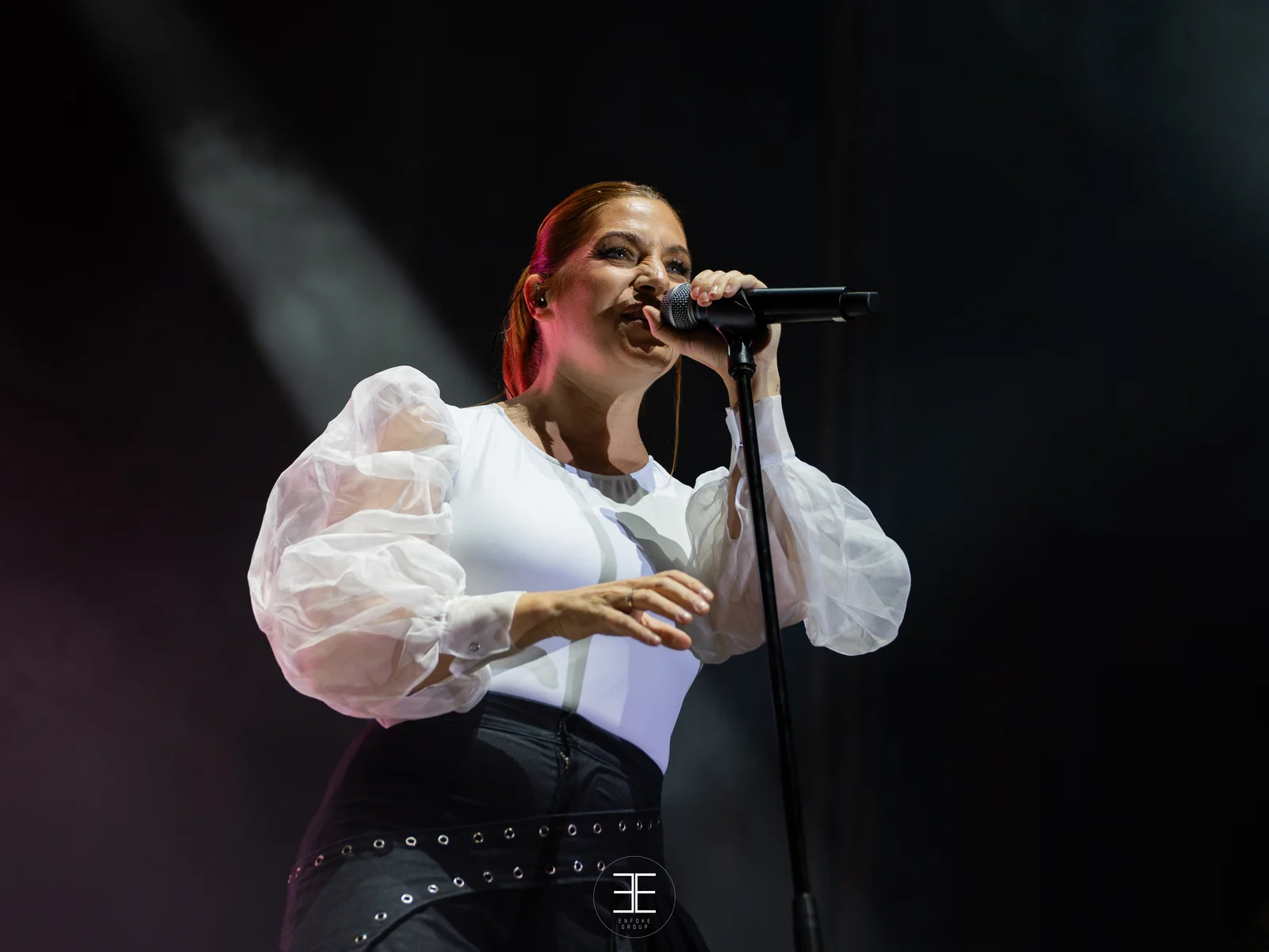 Leire Martínez canta pegada al micrófono del pie, con el brazo recogido