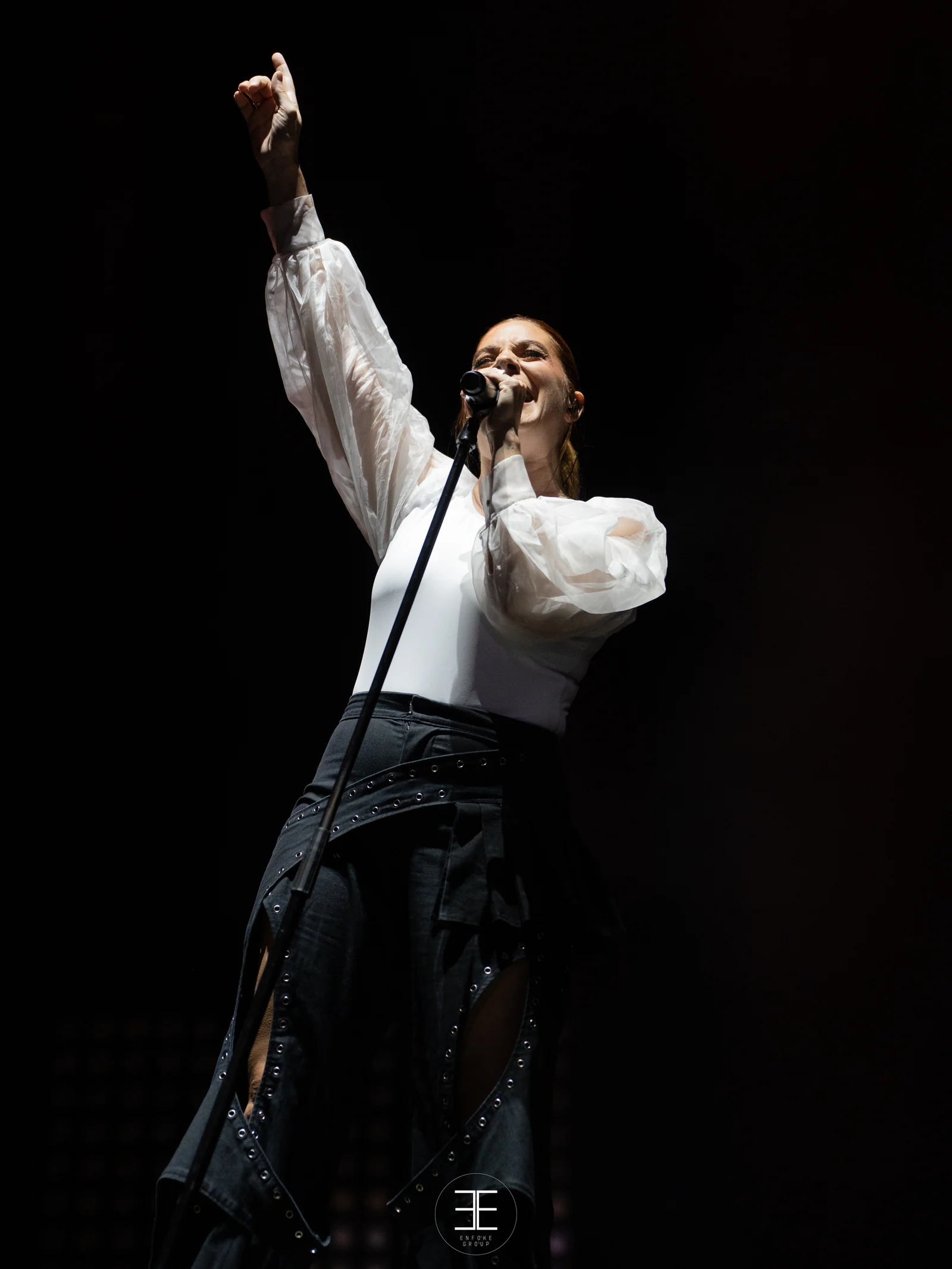 Leire Martínez levanta el puño cantando, en vertical y sobre fondo oscuro