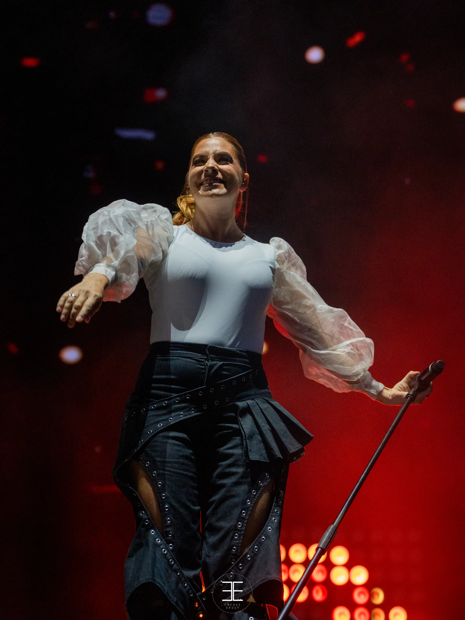 Leire Martínez se ríe con el brazo arriba entre las luces rojas del escenario
