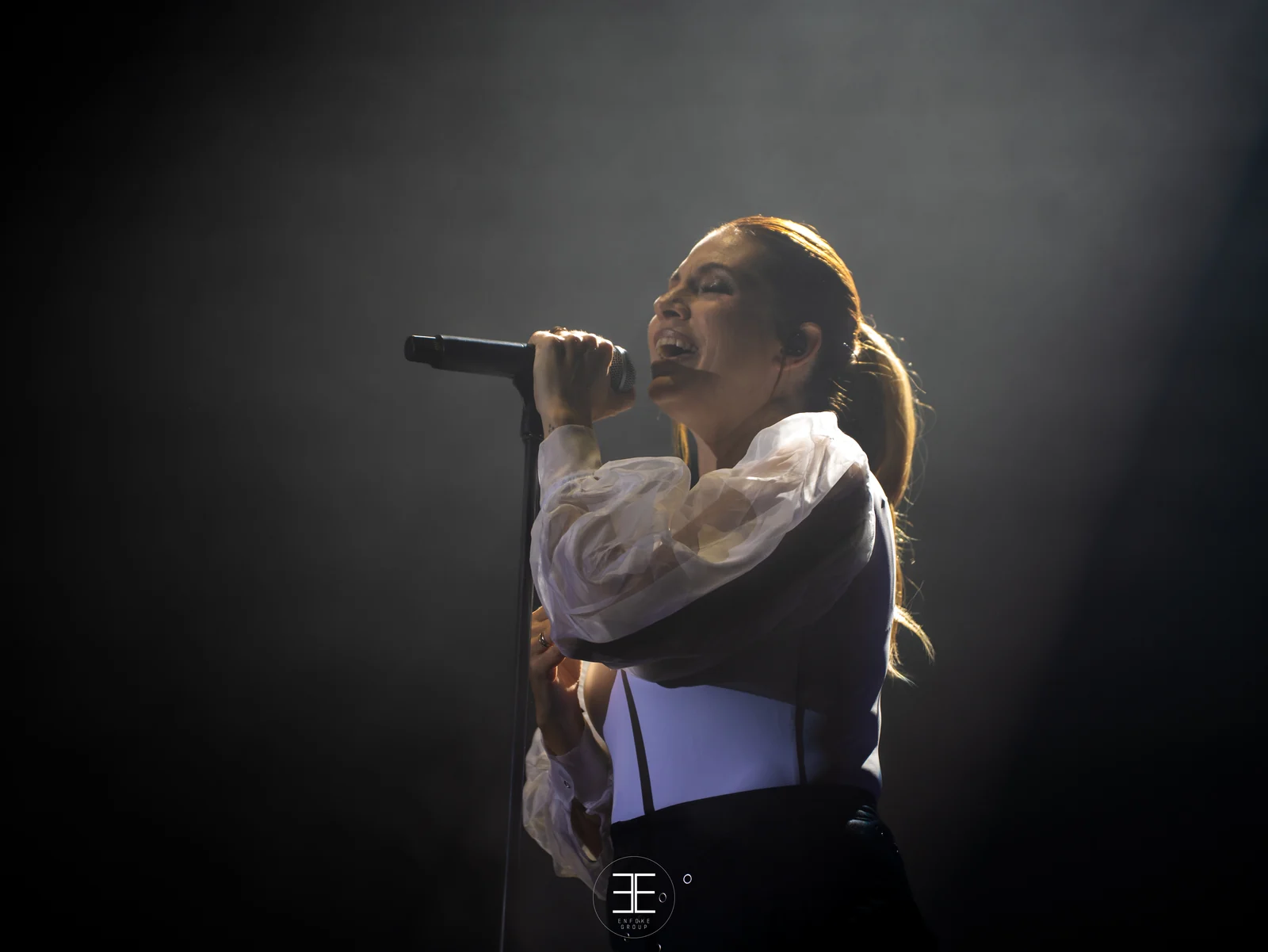 Leire Martínez canta iluminada por una luz lateral suave, con el fondo en penumbra