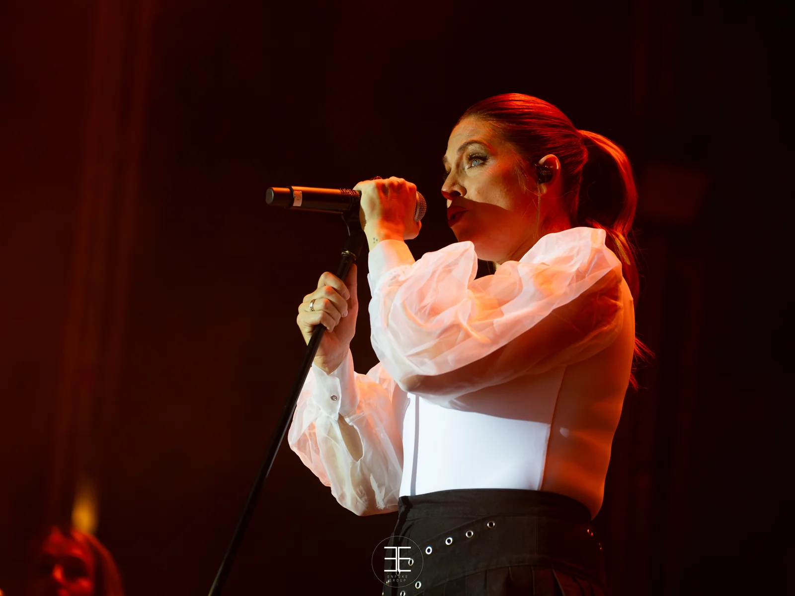 Leire Martínez canta con el micrófono de mano sobre un fondo rojo oscuro