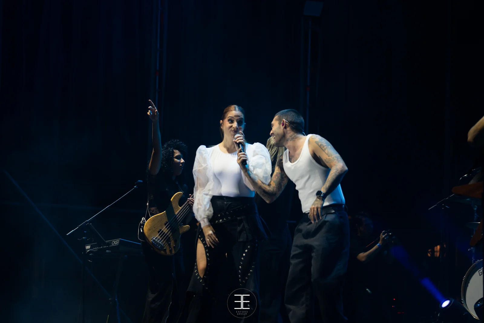 Leire Martínez canta junto al guitarrista, con el resto de la banda detrás en penumbra