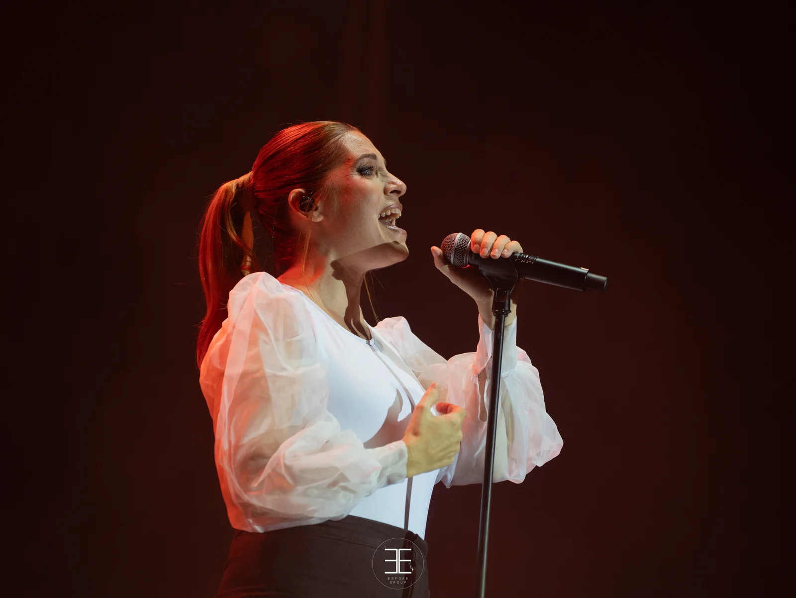 Leire Martínez canta con el micrófono de mano sobre un fondo rojo muy oscuro