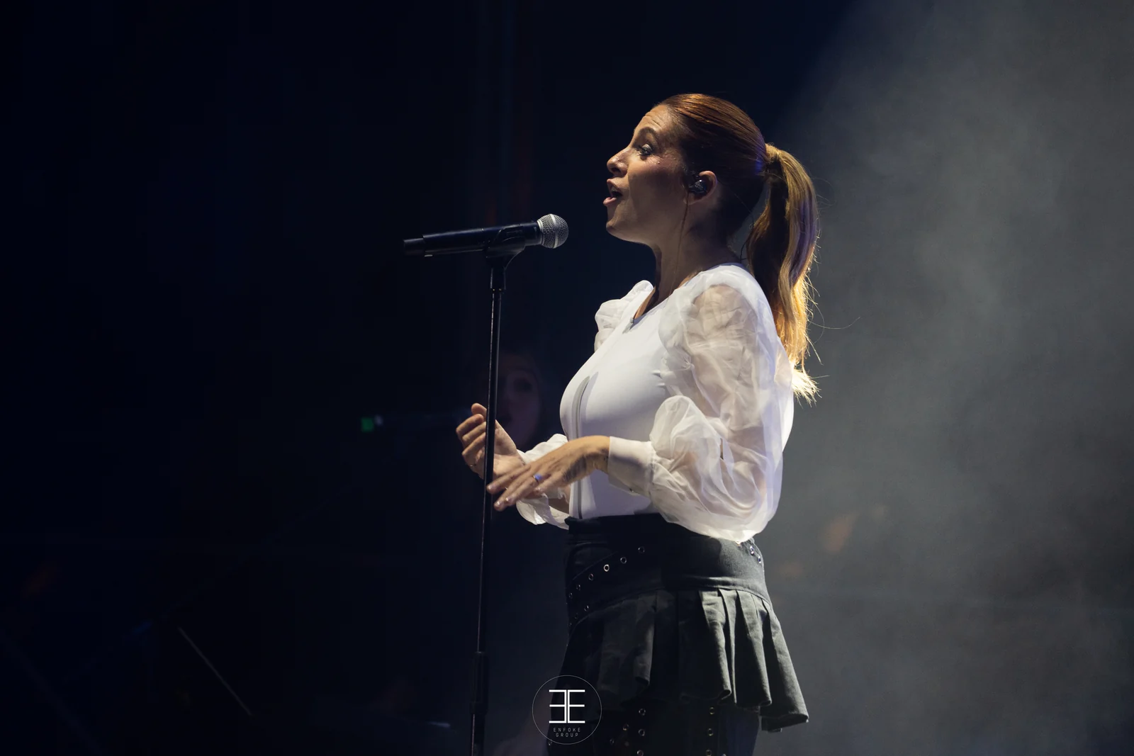 Leire Martínez canta de perfil ante el micrófono de pie, entre humo