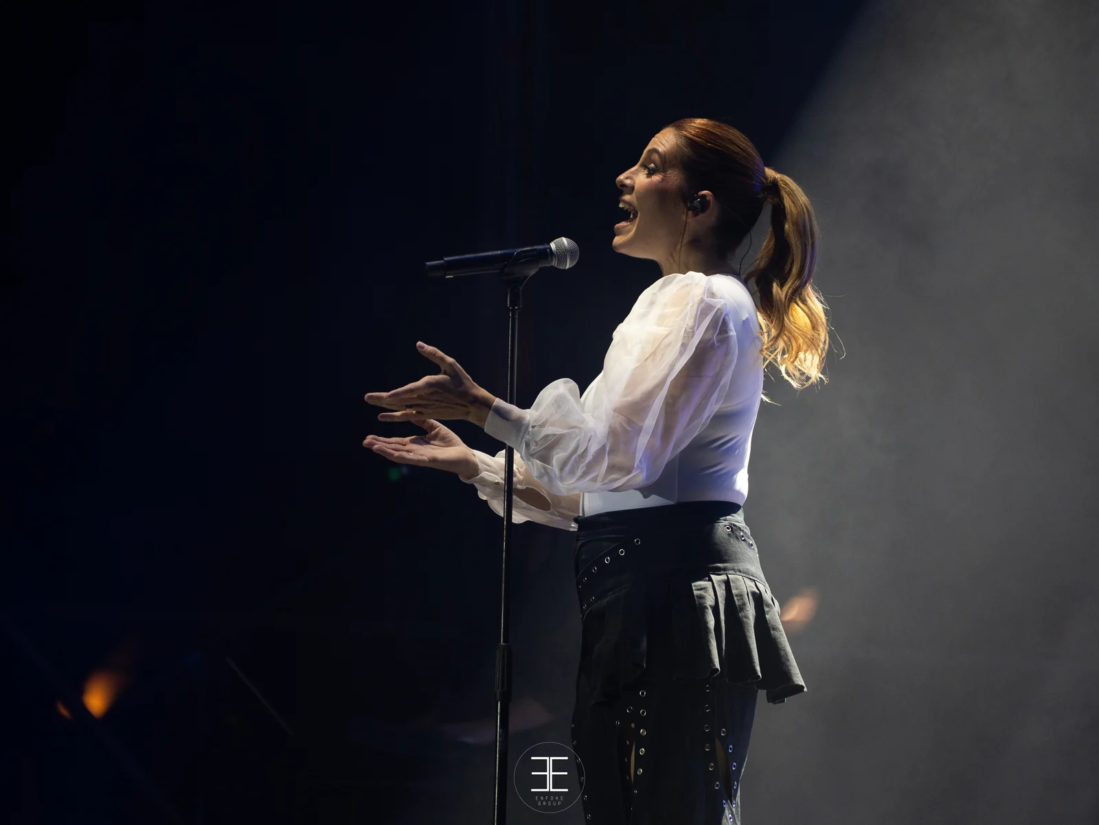 Leire Martínez canta con las manos abiertas hacia delante, entre humo y sin gesto de euforia