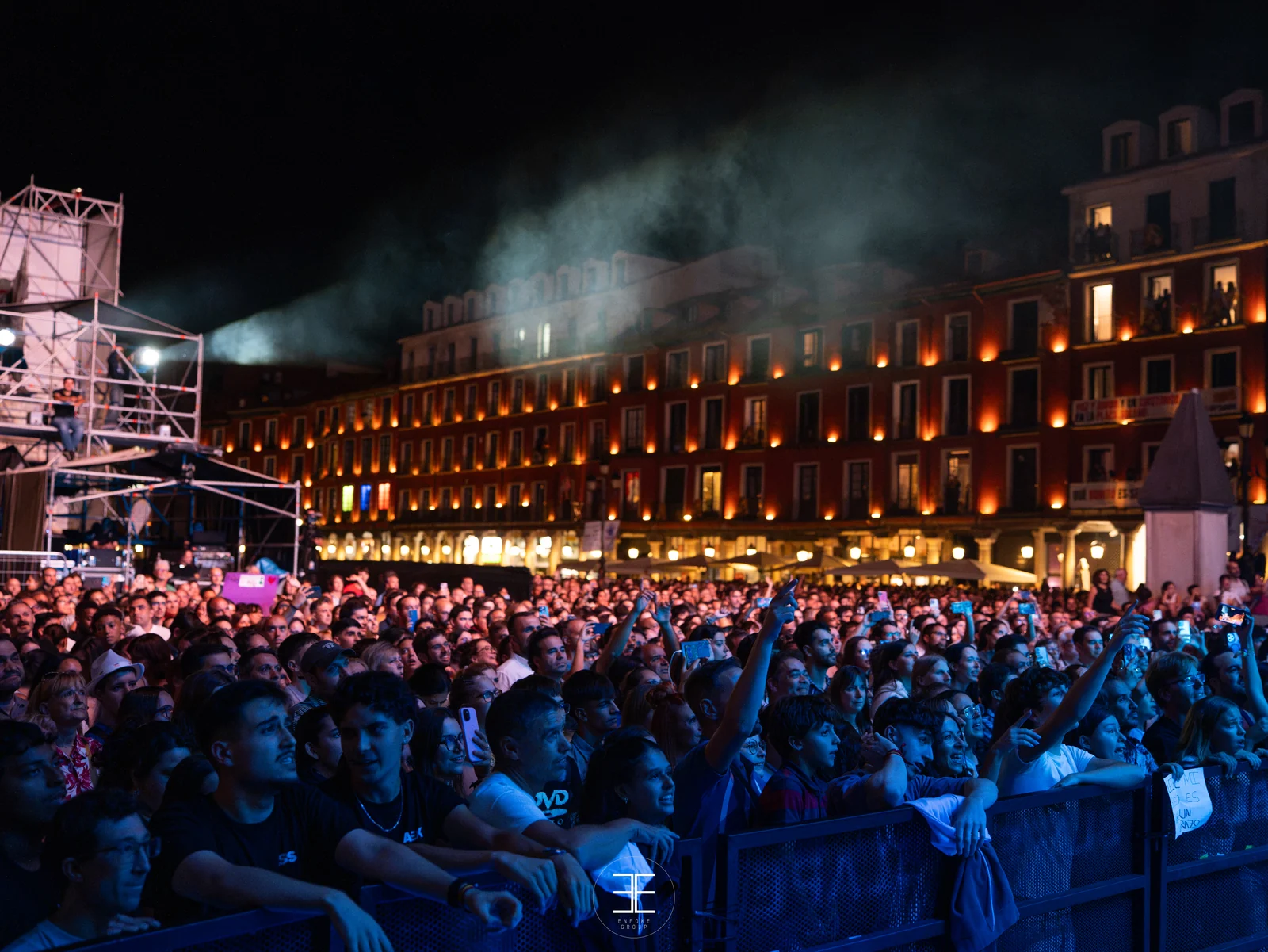 La Plaza Mayor de Valladolid llena de público de noche, con los balcones de la plaza iluminados de naranja detrás