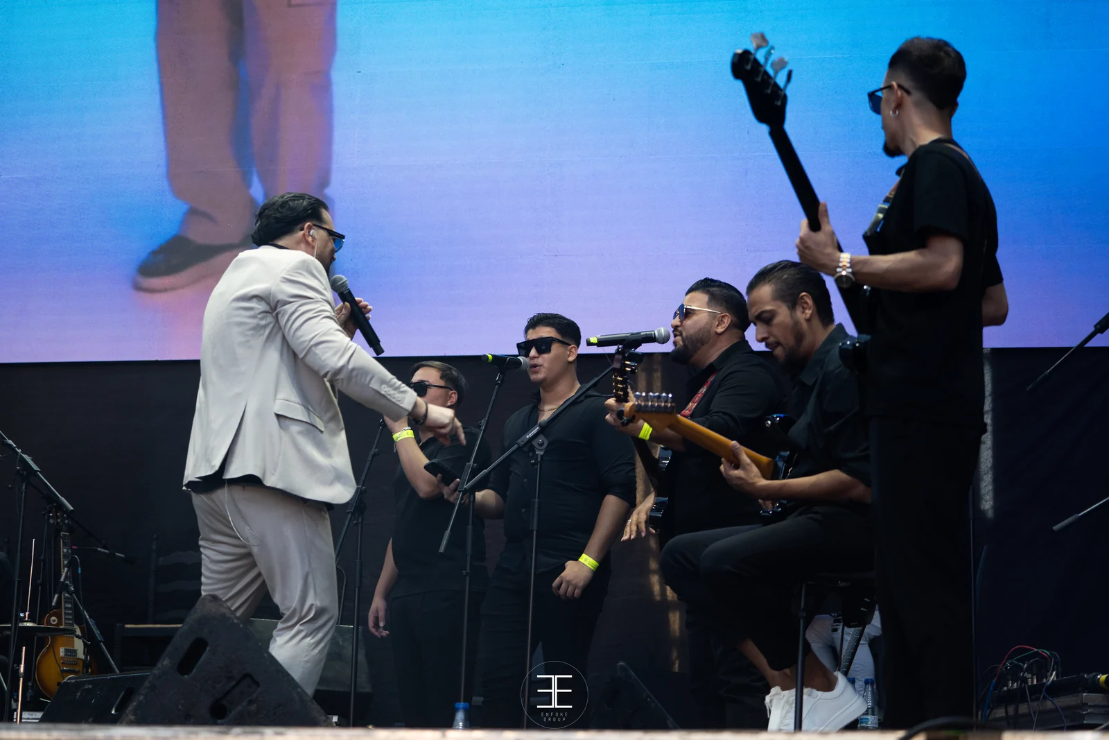 El Pérrez, de espaldas y con micro de mano, se acerca a los músicos: guitarra, bajo y dos voces al micro