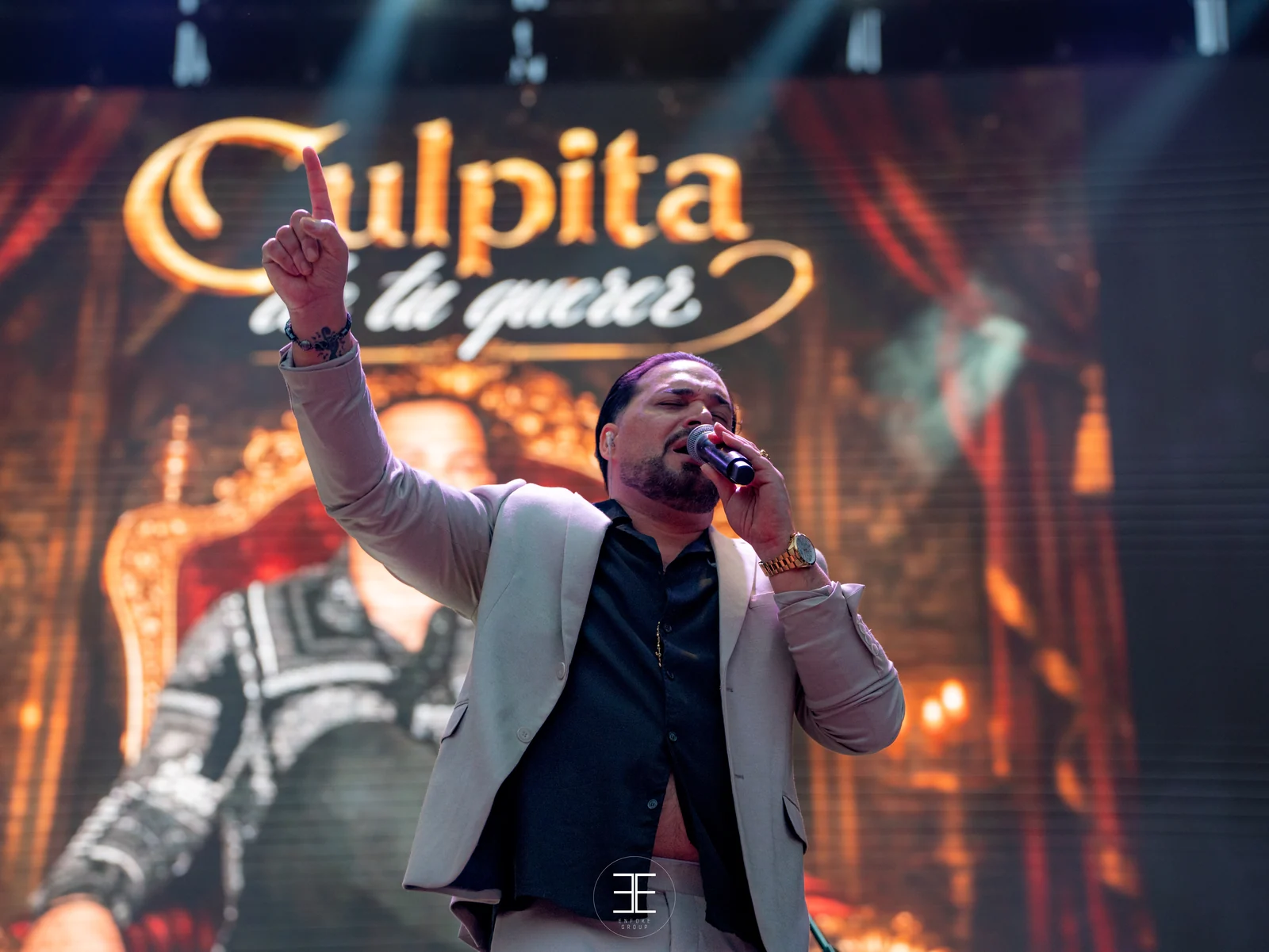 El Pérrez canta con el índice levantado ante una pantalla LED que muestra la portada del disco Culpita de tu querer