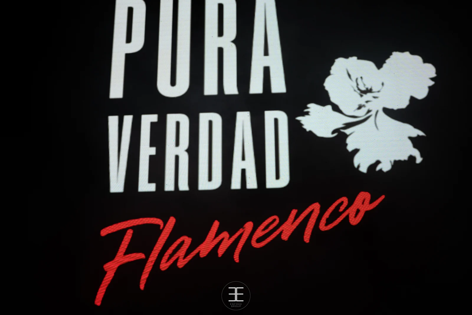 Pantalla LED con el rótulo del espectáculo: Pura Verdad en letras blancas, Flamenco en rojo manuscrito y una flor blanca