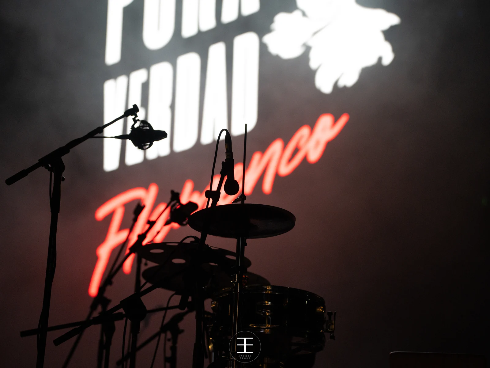 El rótulo Pura Verdad Flamenco al fondo del escenario, con la percusión y varios micrófonos en silueta delante