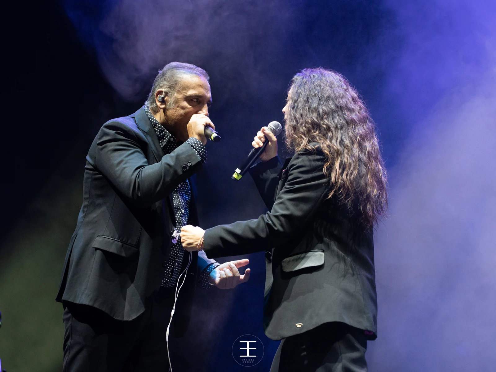 Enrique Heredia «Negri» y Sandra Carrasco frente a frente en el escenario, cada uno con su micrófono; ella, de espaldas a la cámara