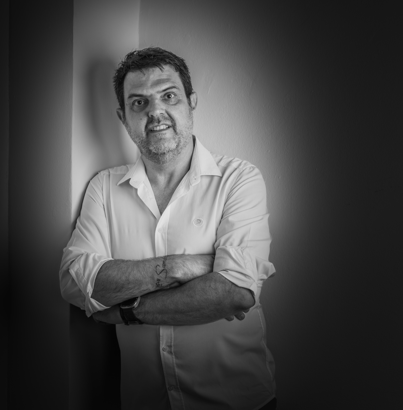 Retrato en blanco y negro de Fernando Fernández Martínez con los brazos cruzados, apoyado en una pared