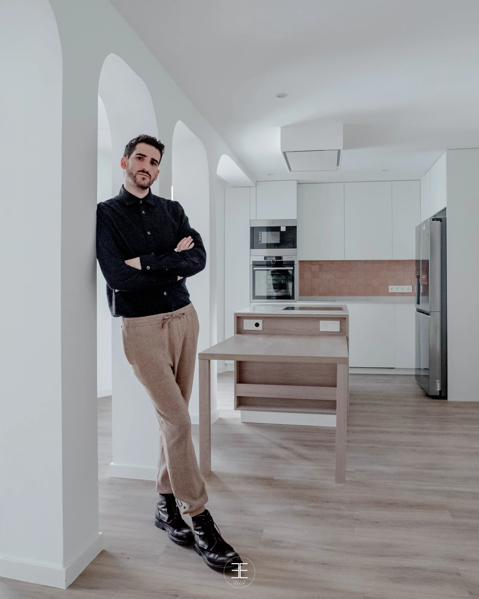 Raúl Almenara de cuerpo entero, con los brazos cruzados y apoyado en un arco, con la cocina al fondo