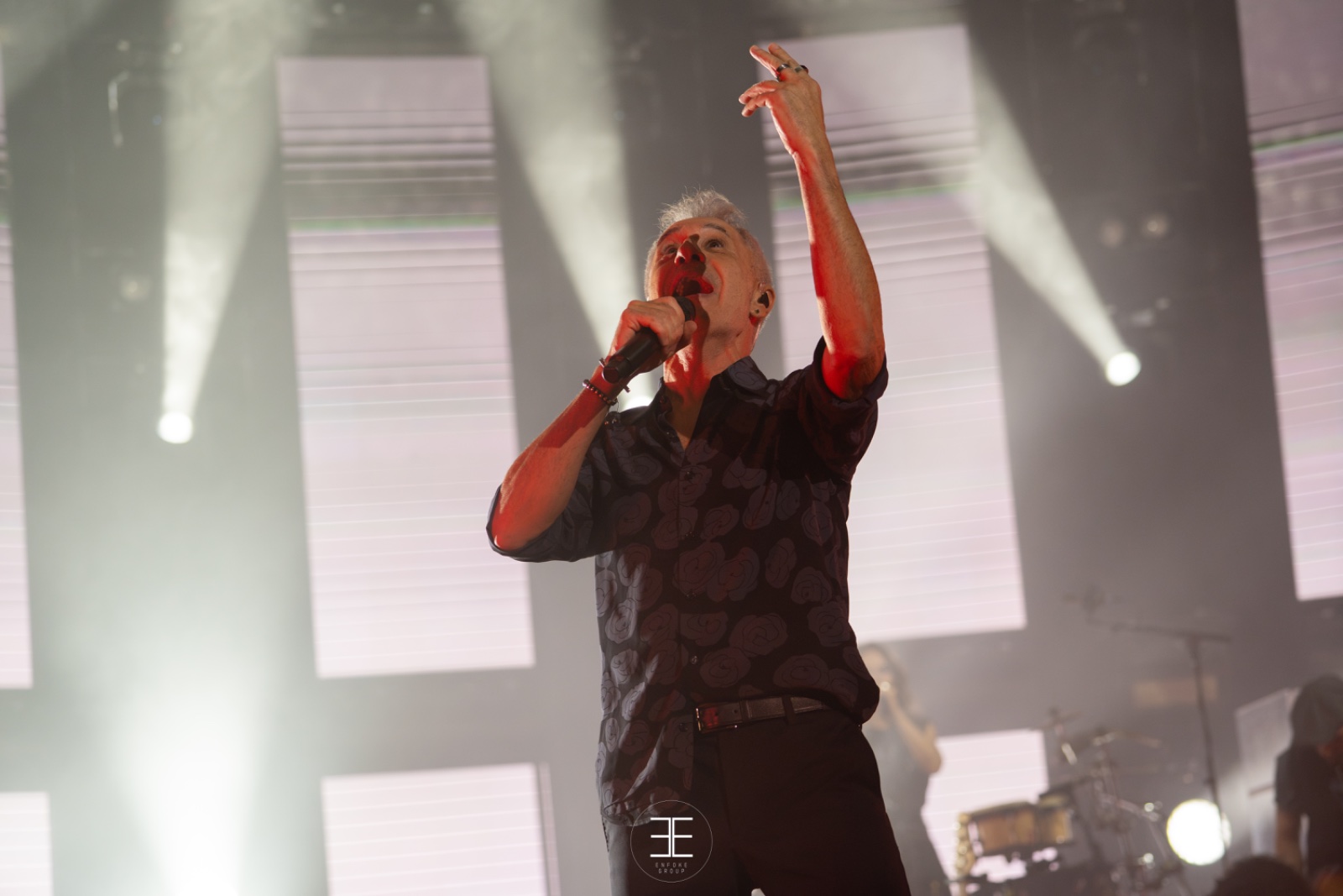 Sergio Dalma canta con el brazo en alto ante pantallas blancas y haces de luz