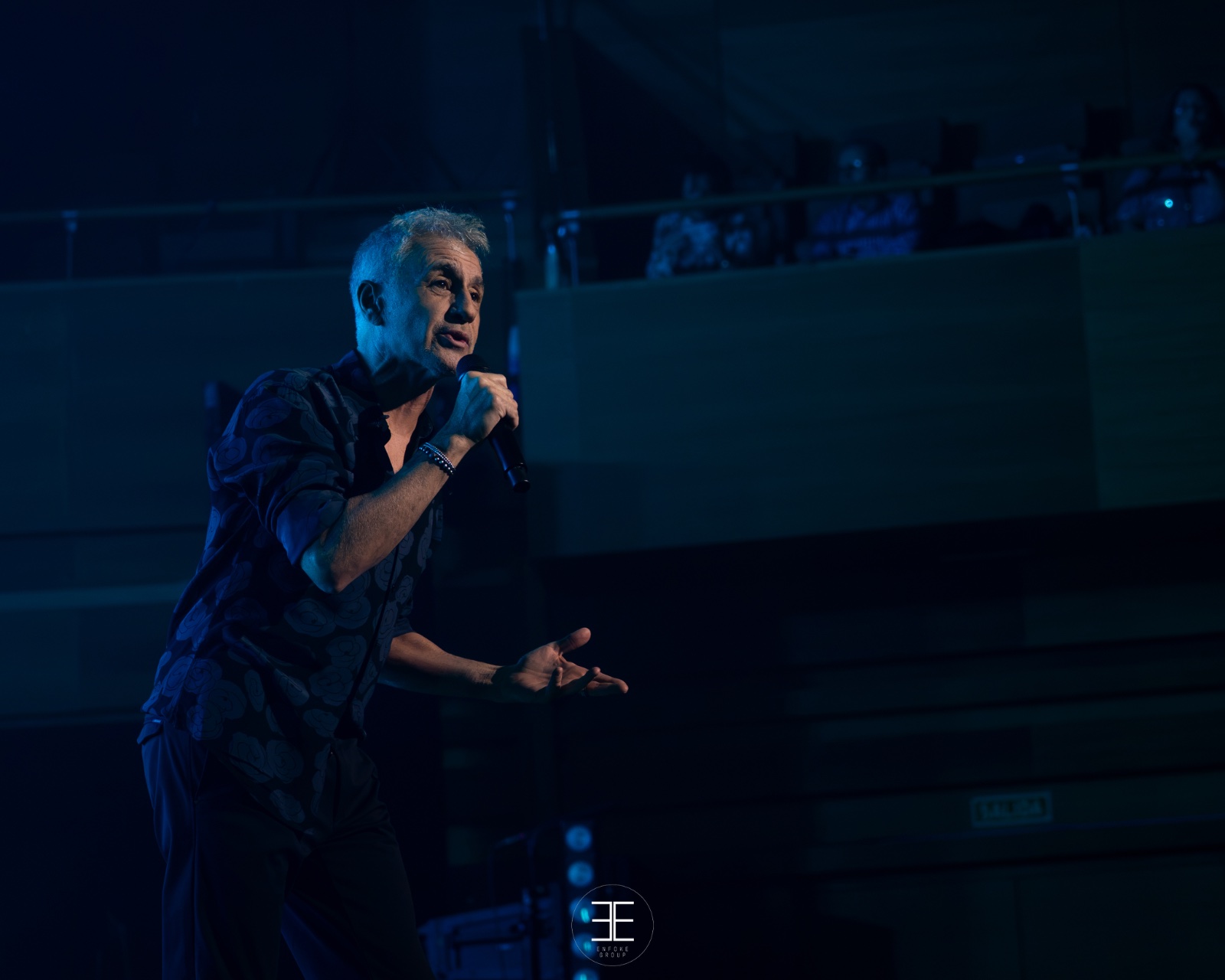Sergio Dalma con el brazo extendido bajo luz azul, con la sala al fondo