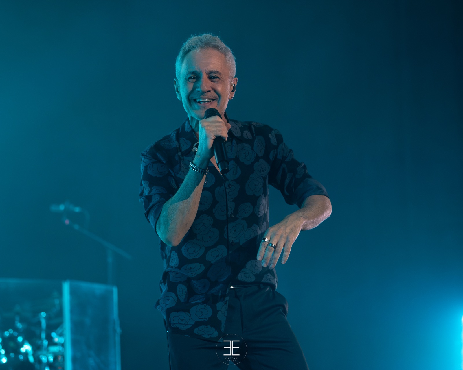Sergio Dalma sonriente, con camisa estampada, bajo luz turquesa
