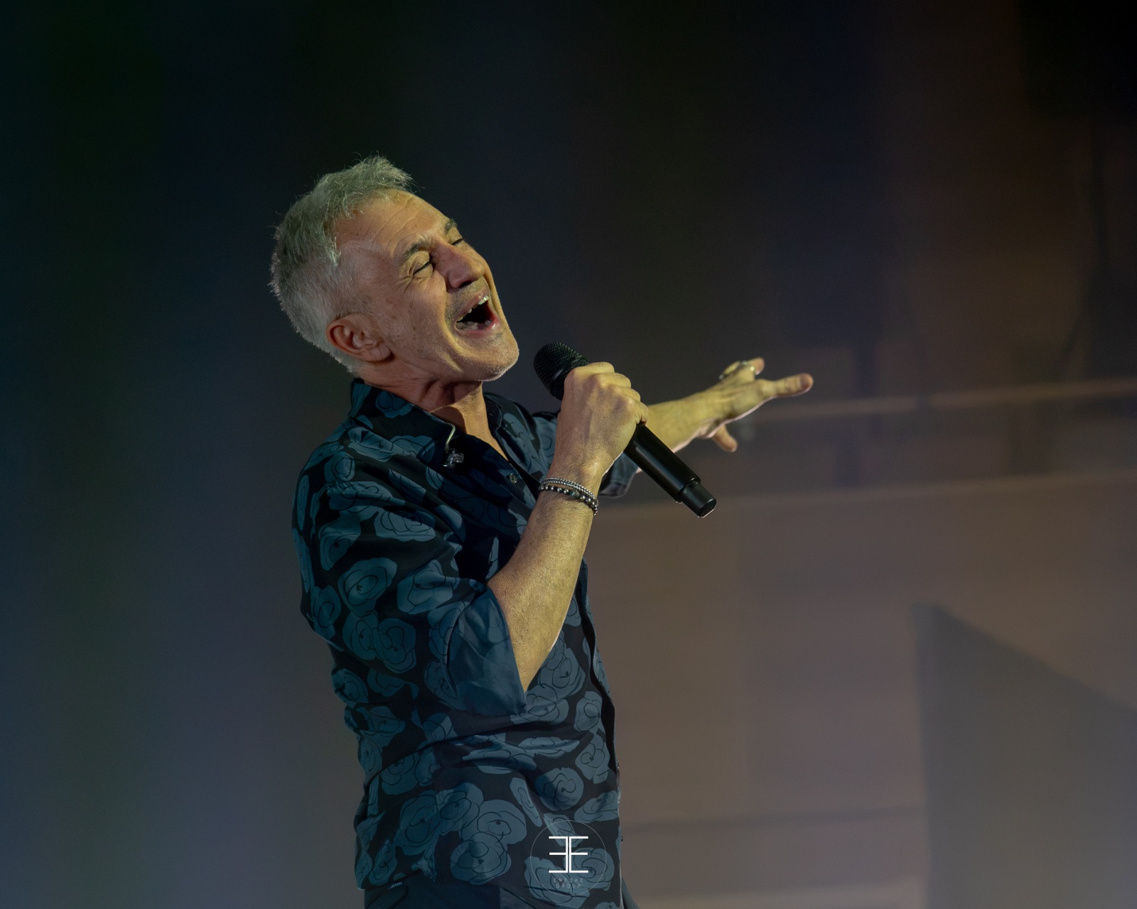 Sergio Dalma canta con fuerza y el brazo extendido, con la pared de la sala detrás
